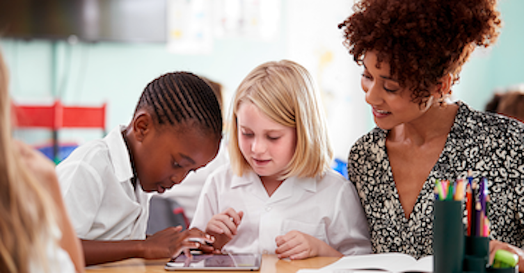 children at a desk in a charter school with their teacher-1